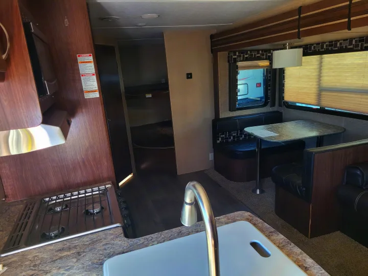 RV rental interior: A cozy space with a full kitchen, dinette seating, and bunk beds visible in the back.. Dutchmen Coleman 2017