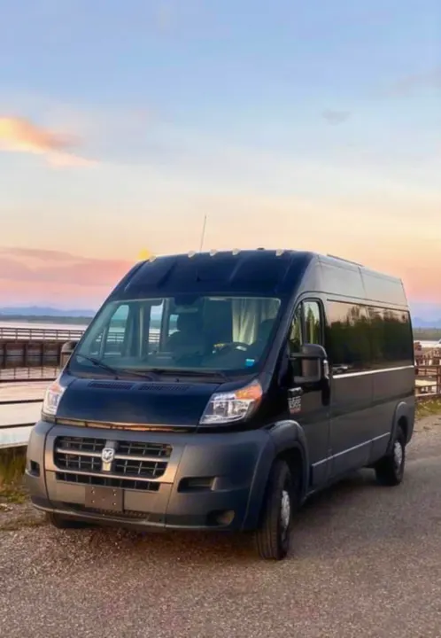 This spacious black camper van, ideal for RV rental adventures, is parked on gravel overlooking a scenic lake at sunset.. Other Other 2015