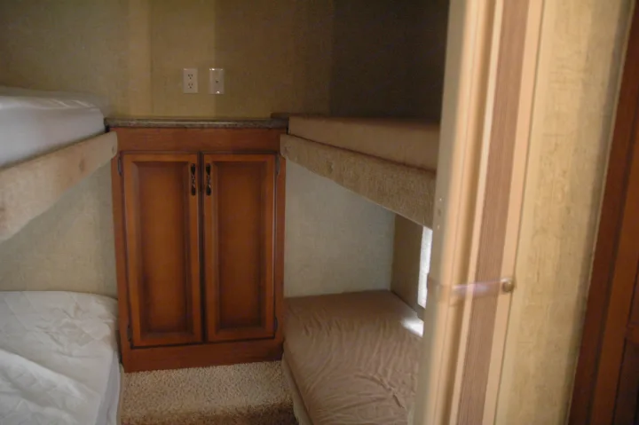 Compact RV rental interior featuring bunk beds, cabinets, and outlets, ideal for family travel or small groups.. Sportsmen Other 2013