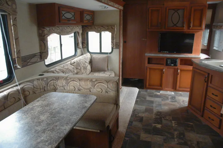 Spacious RV rental interior. Features U-shaped dinette, kitchen, entertainment center, wood cabinets, and large windows.. Sportsmen Other 2013