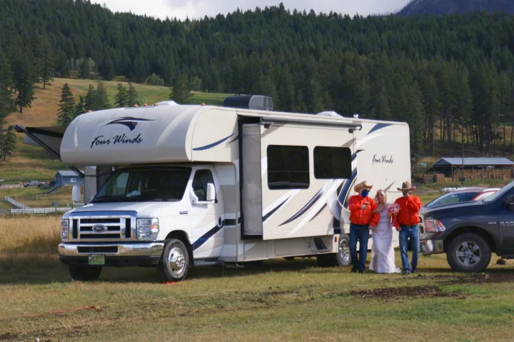 Four Winds RV rental parked in a scenic outdoor setting, with a bride and two men in cowboy hats nearby.. Thor Four Winds 2017