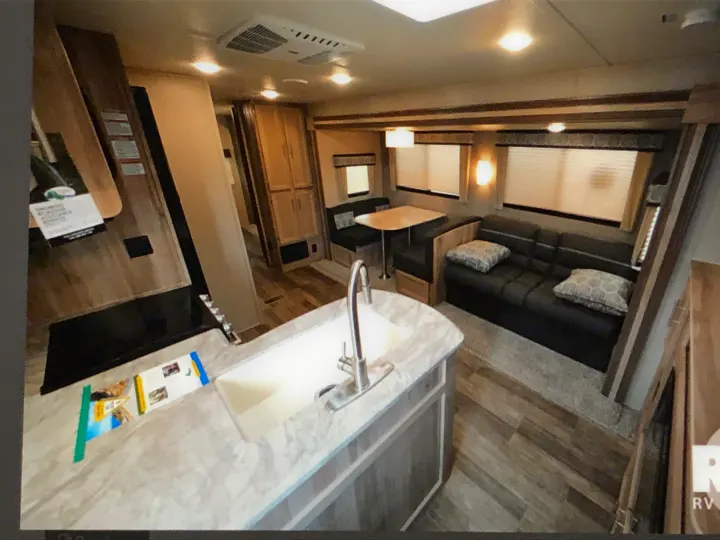 Spacious, modern RV rental interior with kitchen, dining booth, and living room seating for comfortable travel.. Coachmen Catalina 2021