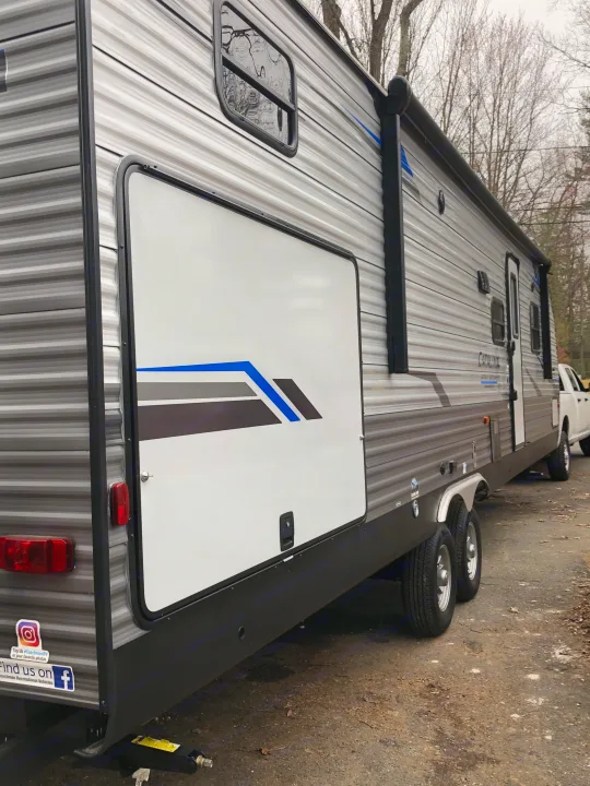 This gray-striped RV rental, a travel trailer with a slide-out, is parked and ready for your next camping adventure.. Coachmen Catalina 2021