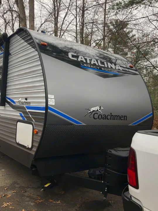 Front of a gray and black Coachmen Catalina rv rental, hitched to a white pickup. Perfect for camping and road trip adventures.. Coachmen Catalina 2021
