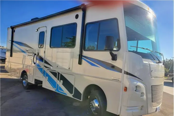 Explore the road in this Winnebago Vista RV rental, a light-colored motorhome with blue and black stripes.. Winnebago Vista 2019