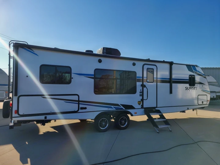 White Sunset Trail travel trailer, great for an RV rental. Features blue accents, multiple windows, and entry steps.. Crossroads Other 2021