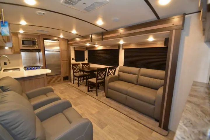 Modern RV rental interior with full kitchen, dining table, and living area featuring sofas and recliners.. Crossroads Other 2021