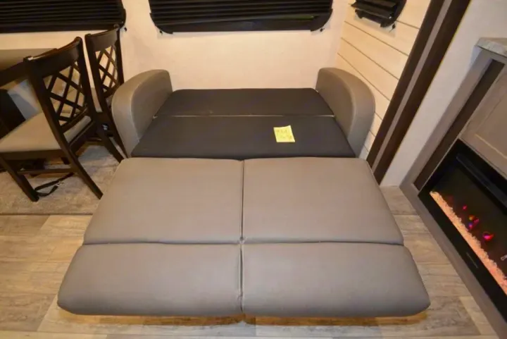 RV rental interior: Sofa converted to bed, with dining chairs & fireplace, showing compact living space.. Crossroads Other 2021