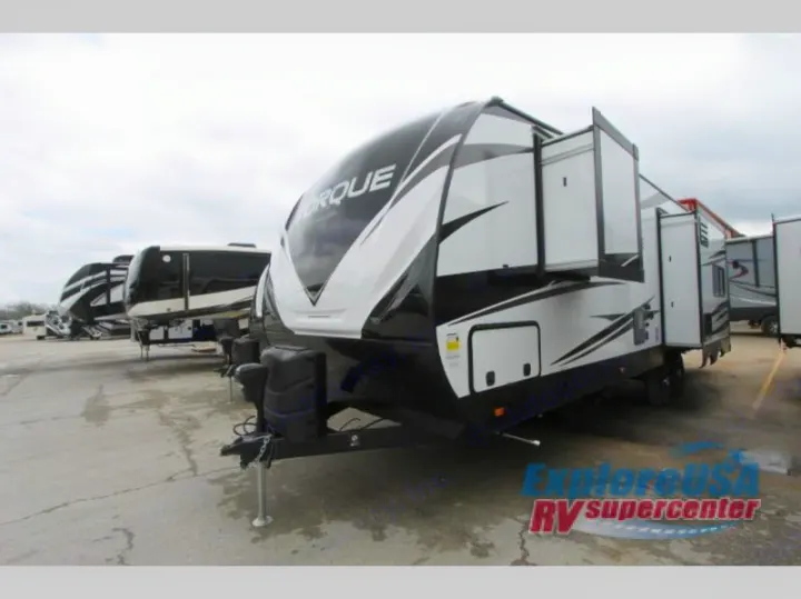 Black and white Torque travel trailer RV with slide-outs extended, among other recreational vehicles. Perfect for your RV rental.. Grand Design Momentum 2020
