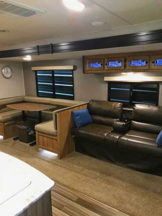 Explore this bright RV rental interior: a comfy dinette, leather couch, and modern cabinets define a spacious living area.. Coachmen Freedom Express 2018
