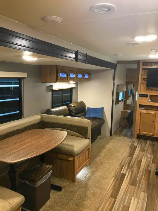 Cozy RV rental interior featuring a dinette, living area with couch, and entertainment center, ideal for travel.. Coachmen Freedom Express 2018