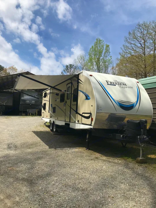 Explore the outdoors! This beige and white Freedom Express travel trailer with an extended awning is available for RV rental.. Coachmen Freedom Express 2018