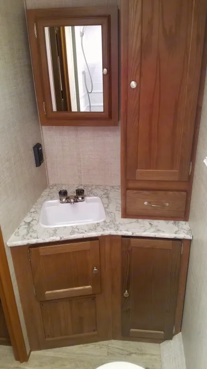 RV rental bathroom: compact vanity with sink, mirror, and wooden storage cabinets for efficient use of space.. Gulf Stream Gulf Breeze Ultra Lite 2021