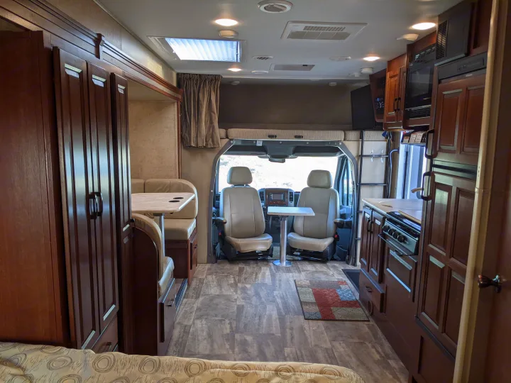 Spacious RV rental interior with dinette, kitchen, & cab. Features include wood cabinets, cozy seating, & skylight.. Forest River Sunseeker 2016