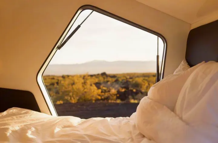 Cozy bed inside an RV rental. Wake up to panoramic mountain and desert views through the unique window, perfect for travel.. Polydrop K-20 2020