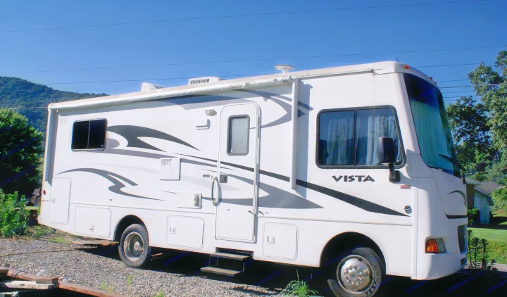 Spacious white Vista RV rental parked on gravel under a clear blue sky, ideal for your next travel adventure.. Winnebago Vista 2013
