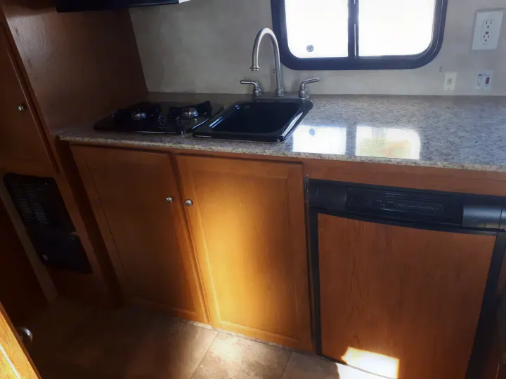 RV rental kitchen: a practical compact space with a two-burner stove, sink, and refrigerator unit.. Coachmen Clipper 2013