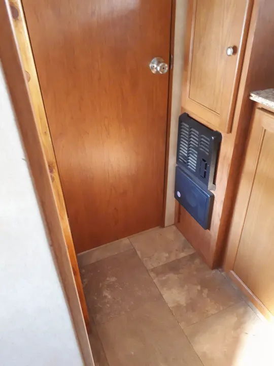 RV rental interior featuring a warm wooden door, built-in cabinetry, and a wall-mounted furnace or electrical panel.. Coachmen Clipper 2013