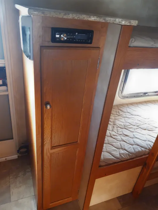 RV rental: Interior showing wooden cabinet, integrated stereo, and bunk beds with window and quilted mattress.. Coachmen Clipper 2013