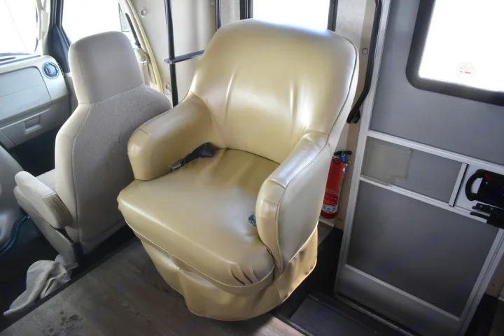 Spacious RV rental interior: tan swivel captain's chair, passenger seat, and safety fire extinguisher.. Forest River Sunseeker 2018