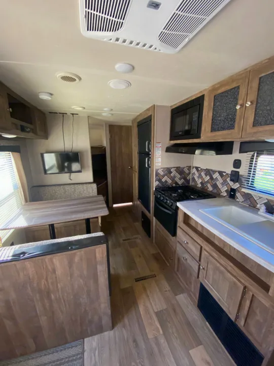 RV rental interior: A bright, modern space with a full kitchen, dinette, TV area, and warm wood finishes throughout.. Forest River Puma 2019