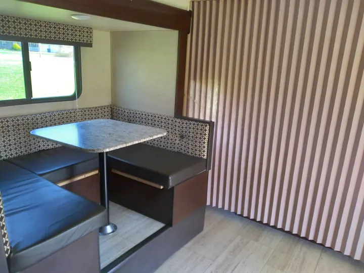 RV rental dinette: U-shaped seating, granite-look table, window, and pleated privacy curtain.. KZ Other 2017