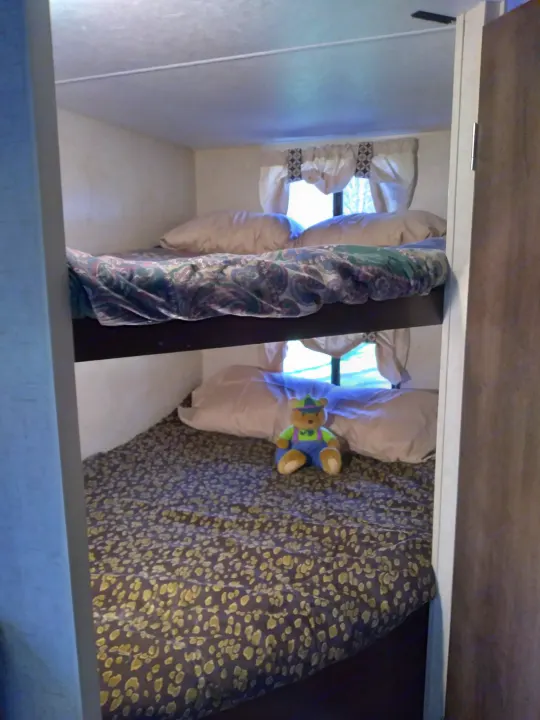 Cozy RV rental bunk beds offer comfortable sleeping for travel, with a cute teddy bear on the bottom bunk.. KZ Other 2017