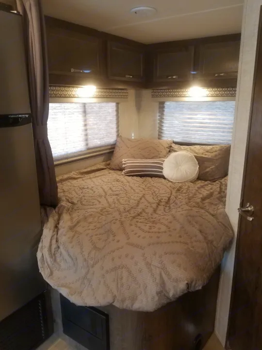 Experience comfort in this cozy rv rental bedroom, featuring a plush bed, windows, and dark wood cabinetry.. Gulf Stream Conquest 2021