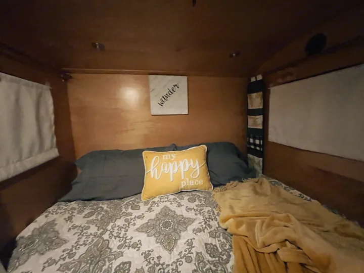 Cozy RV rental bedroom with a comfy bed, "my happy place" pillow, and "wander" sign for comfortable travel.. American Teardrop Travel Trailer 2016