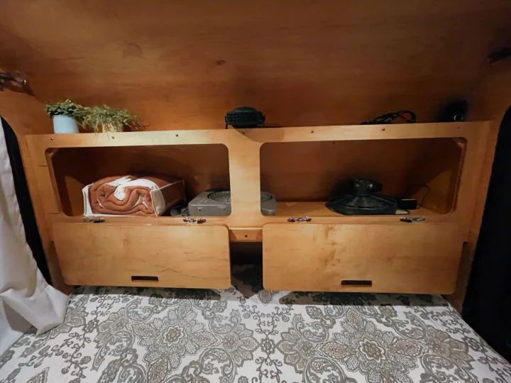 Cozy RV rental sleeping nook: patterned bed, integrated wooden shelves with blankets & fans for convenience.. American Teardrop Travel Trailer 2016