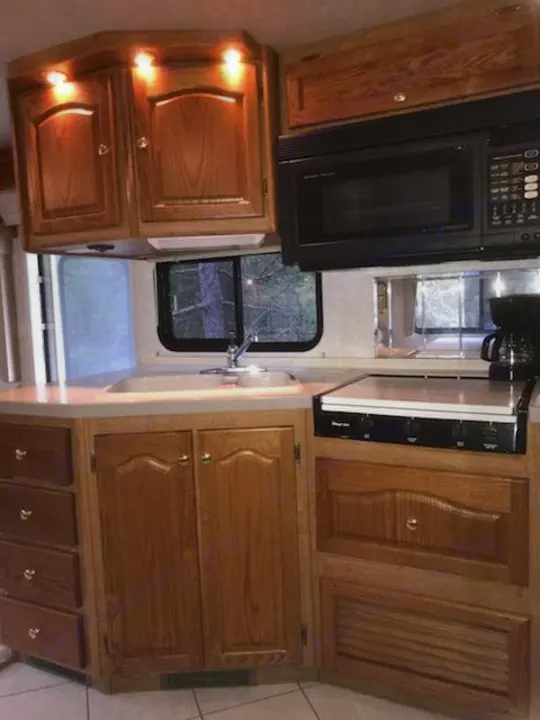 Spacious wood RV kitchen, featuring a microwave, sink, and stovetop, ideal for your next RV rental journey.. Tiffin Motorhomes Allegro Bay 2001