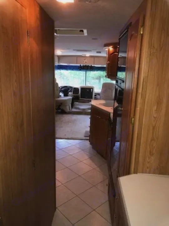 Inside an RV rental: View down the aisle showing the kitchen, tiled floor, and front cockpit with a large window.. Tiffin Motorhomes Allegro Bay 2001