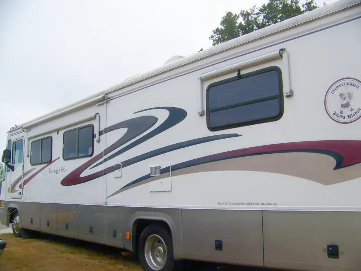 A white Allegro Bay motorhome RV rental, featuring unique graphic decals and a "Polka Mobile" emblem, parked for travel.. Tiffin Motorhomes Allegro Bay 2001