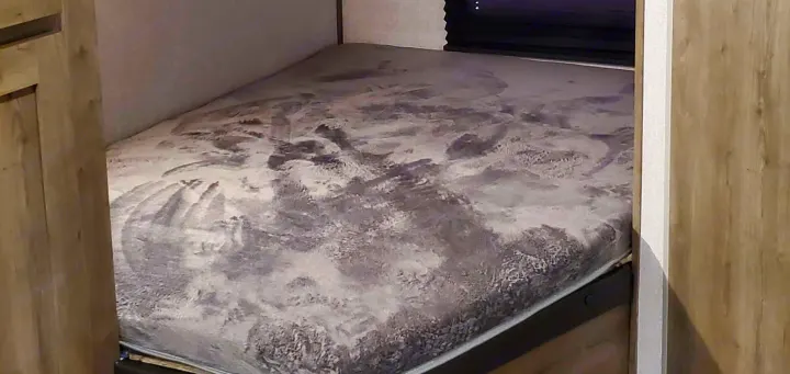 RV rental: A cozy sleeping area with a textured grey and white mattress, built into the compact RV interior.. Dutchmen Aspen Trail 26BH 2021