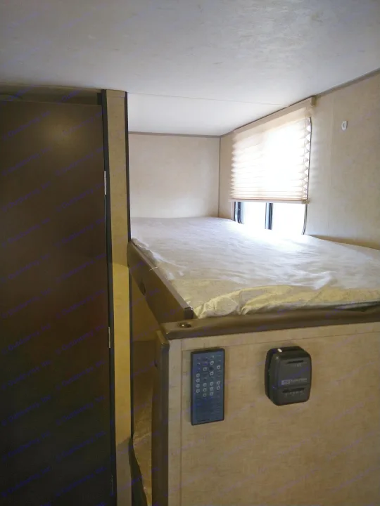 Inside an RV rental: a compact bunk area with a window shade, control panel, and space below.. Forest River Cherokee Wolf Pup 2017