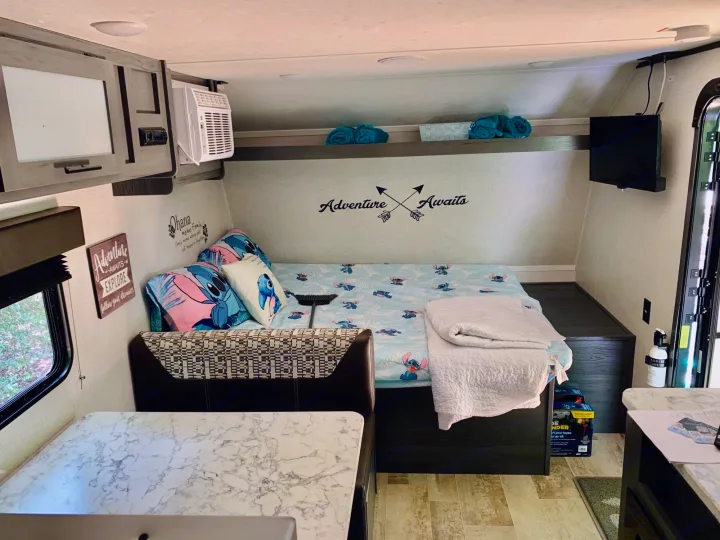 Cozy Stitch-themed RV rental interior featuring a bed, dining area, and media system, ideal for your next adventure.. Aspen Other 2021