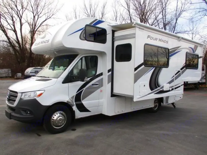 A Four Winds Class C RV rental, white with blue/gray graphics, on a Mercedes-Benz Sprinter chassis with a slide-out extended.. Thor Motor Coach Four Winds Sprinter 2021