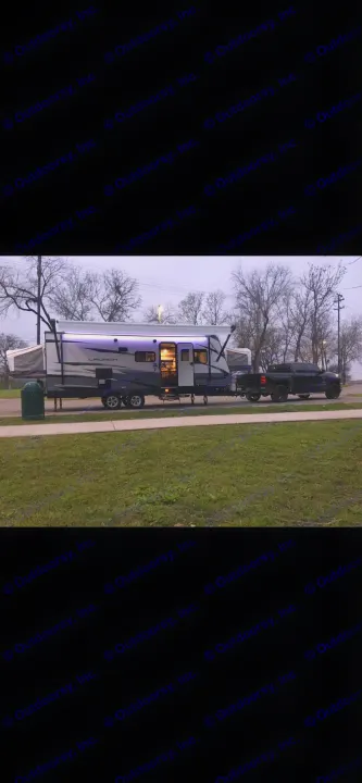 A cozy rv rental: modern travel trailer with illuminated awning and pop-outs, hooked to a pickup truck, parked at dusk.. Starcraft Launch 2018
