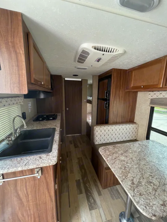 RV rental interior with a modern kitchen (sink, stove, counter), dinette, and refrigerator, ideal for travel.. Viking 21BH 2018