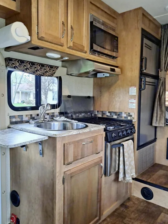 This rv rental's practical kitchen offers a sink, stove, microwave, and fridge, perfect for your adventures.. Gulf Stream Conquest 2018