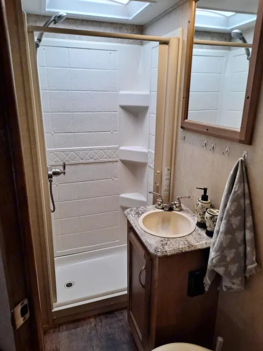 Compact rv rental bathroom with a vanity, sink, mirror, and shower stall, designed for convenient travel.. Gulf Stream Conquest 2018