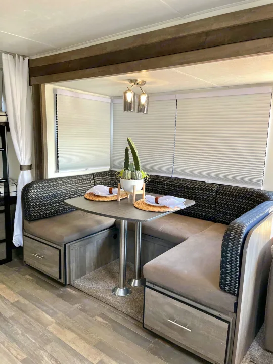 Modern RV rental dinette with cozy U-shaped seating, table set for two, and sleek decor.. Forest River Vibe 2021