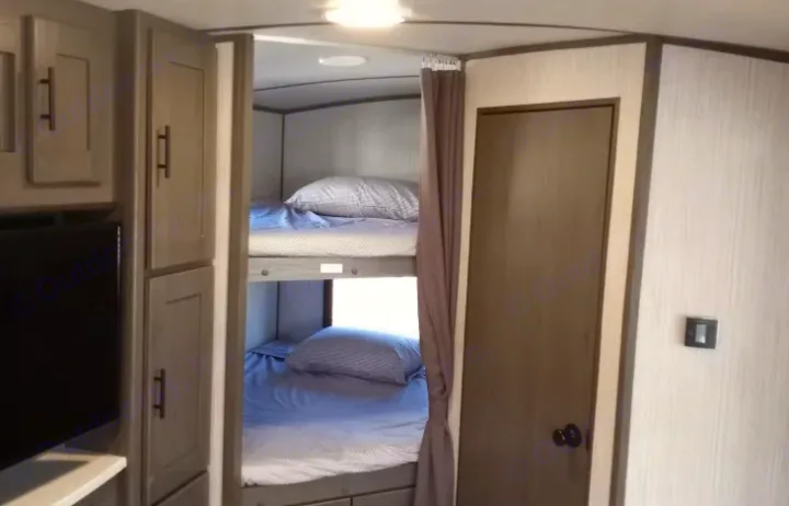 Cozy RV rental interior featuring modern bunk beds, storage cabinets, and a side door.. Cruiser RV MPG Ultra Lite 2021