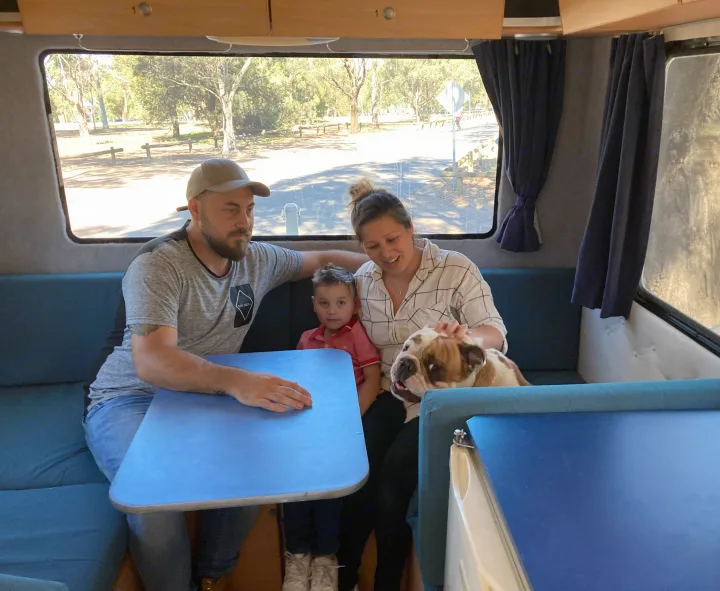 A happy family, including a young boy and their bulldog, relaxing at the dinette of their RV rental.. Mercedes Dreamseeker River 6 2008
