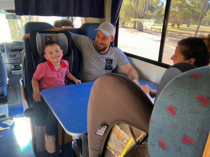 Happy family inside their RV rental: father, son in car seat, and mother. Great view from the camper window!. Mercedes Dreamseeker River 6 2008