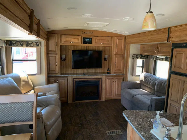 Spacious RV rental living area with TV, fireplace, sofas & kitchen. Home-like comfort on the road.. Keystone Laredo 2015
