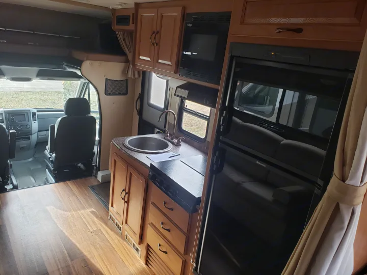 Interior of an RV rental, showcasing the well-equipped kitchen, living area, and front cab. Ideal for road trips.. Coachmen Prism 2150LE 2013