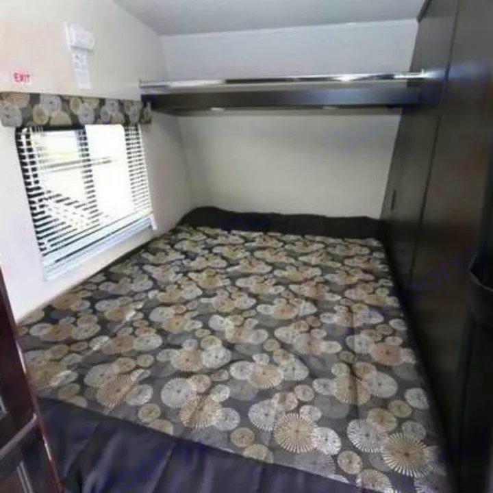 Comfortable RV rental bedroom with a patterned bed, window, and overhead storage. Ideal for cozy travel accommodations.. Genesis Supreme Rv Genesis Supreme 2021