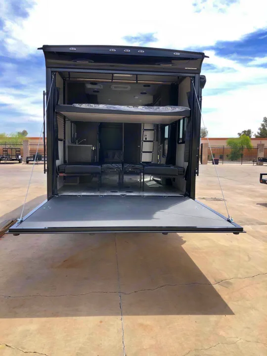 Explore this toy hauler RV rental interior. Rear ramp down reveals bunk beds & sofa seating, ready for adventure.. Genesis Supreme Rv Genesis Supreme 2021
