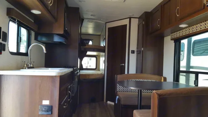 RV rental interior showing a kitchen with sink, stove, microwave, bunk beds, and a dinette area.. Jayco Jay Flight 2018